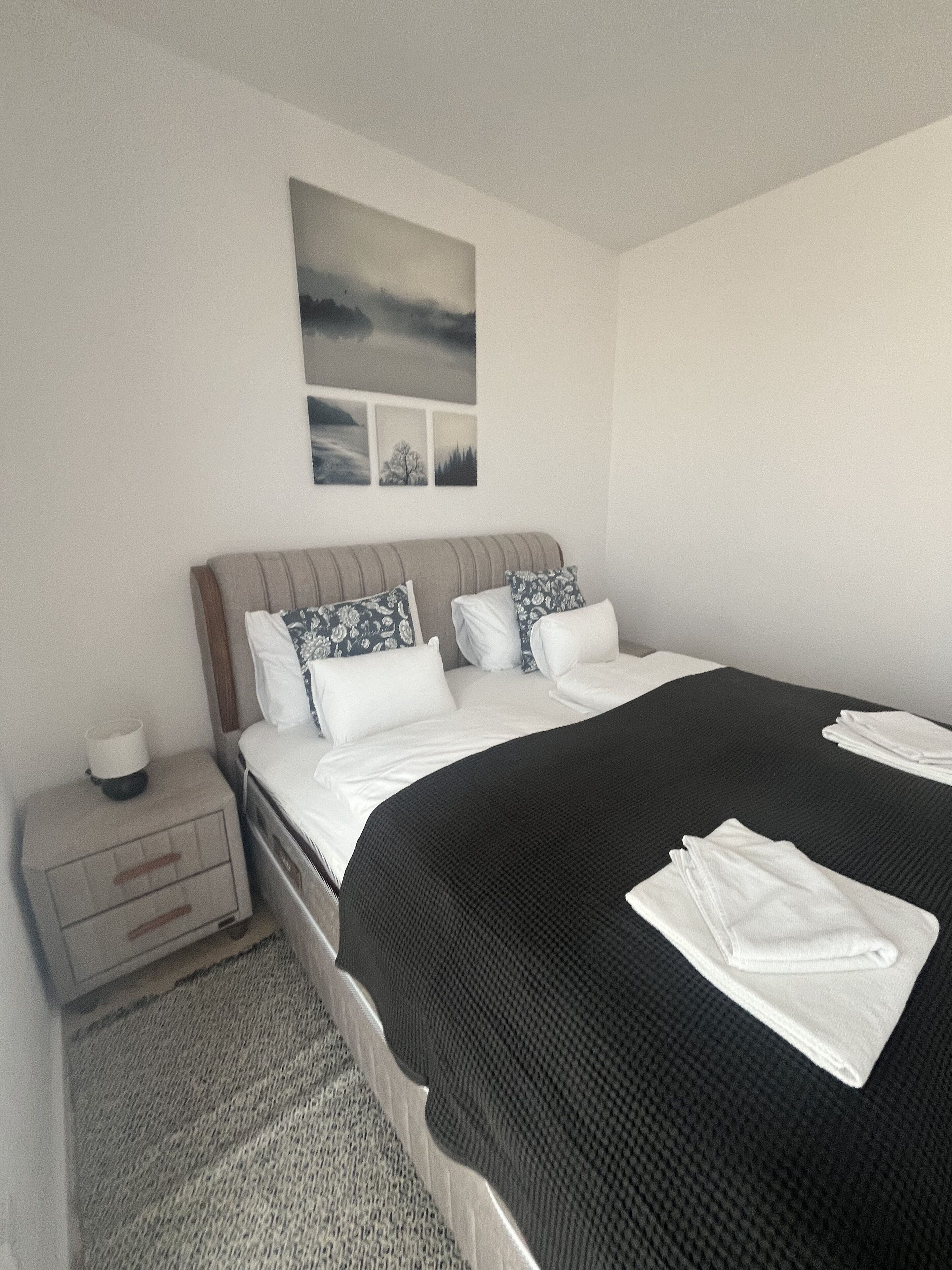 A neatly arranged bedroom with a bed, pillows, a bedside table, and a wall-mounted picture.