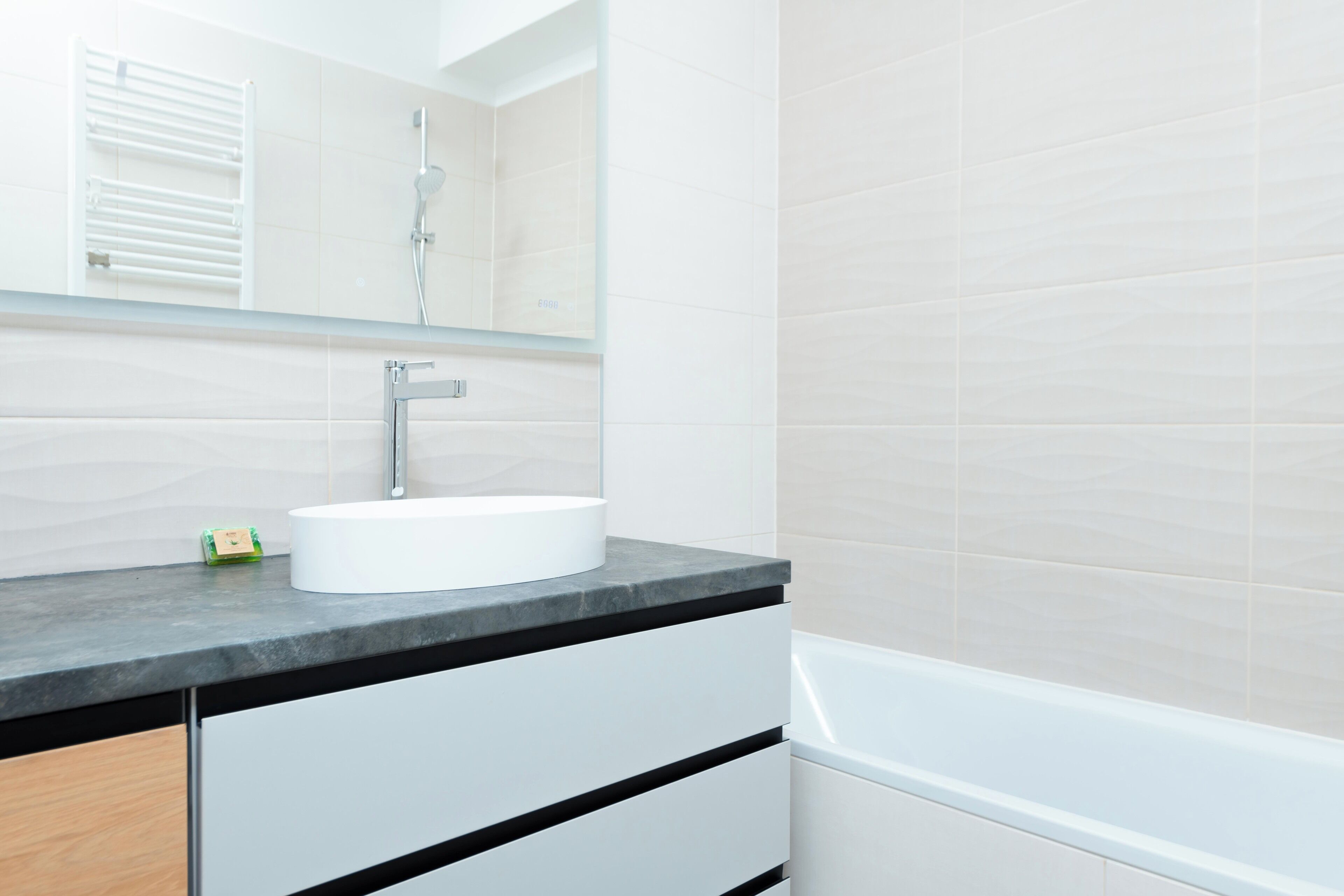 Un baño moderno con un lavamanos blanco, un espejo y una bañera.