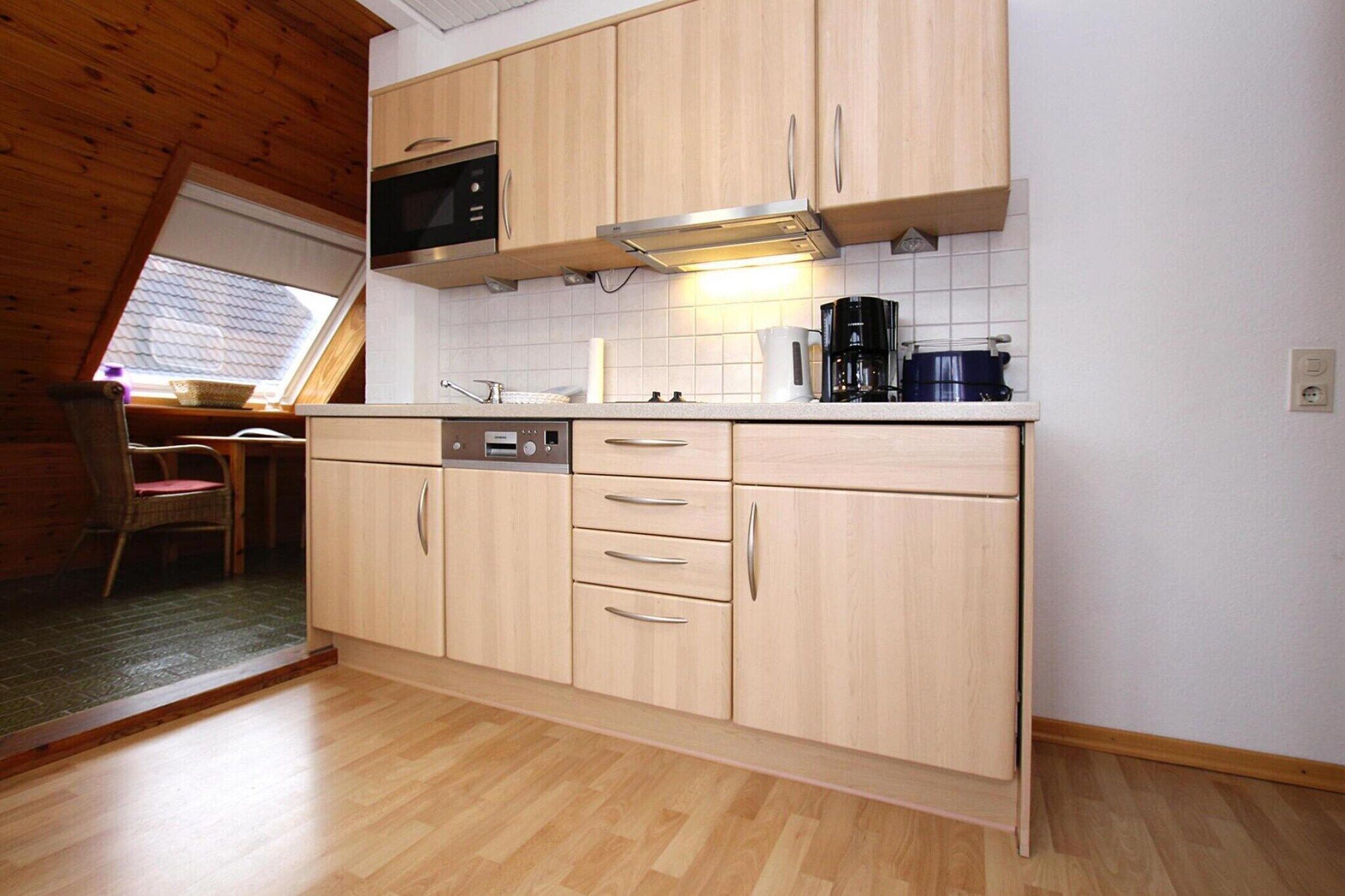 Una cocina con armarios de madera, un microondas, una cafetera y un ventanal con vistas.