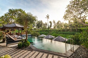 A poolside area with lounge chairs, umbrellas, and a clear view of the pool. - Mayura Ubud Retreat (Mas)