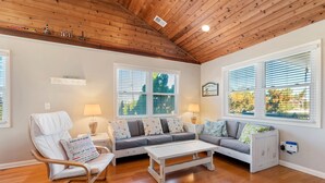 A living room with a wooden ceiling, two sofas, a white coffee table, and a white chair.