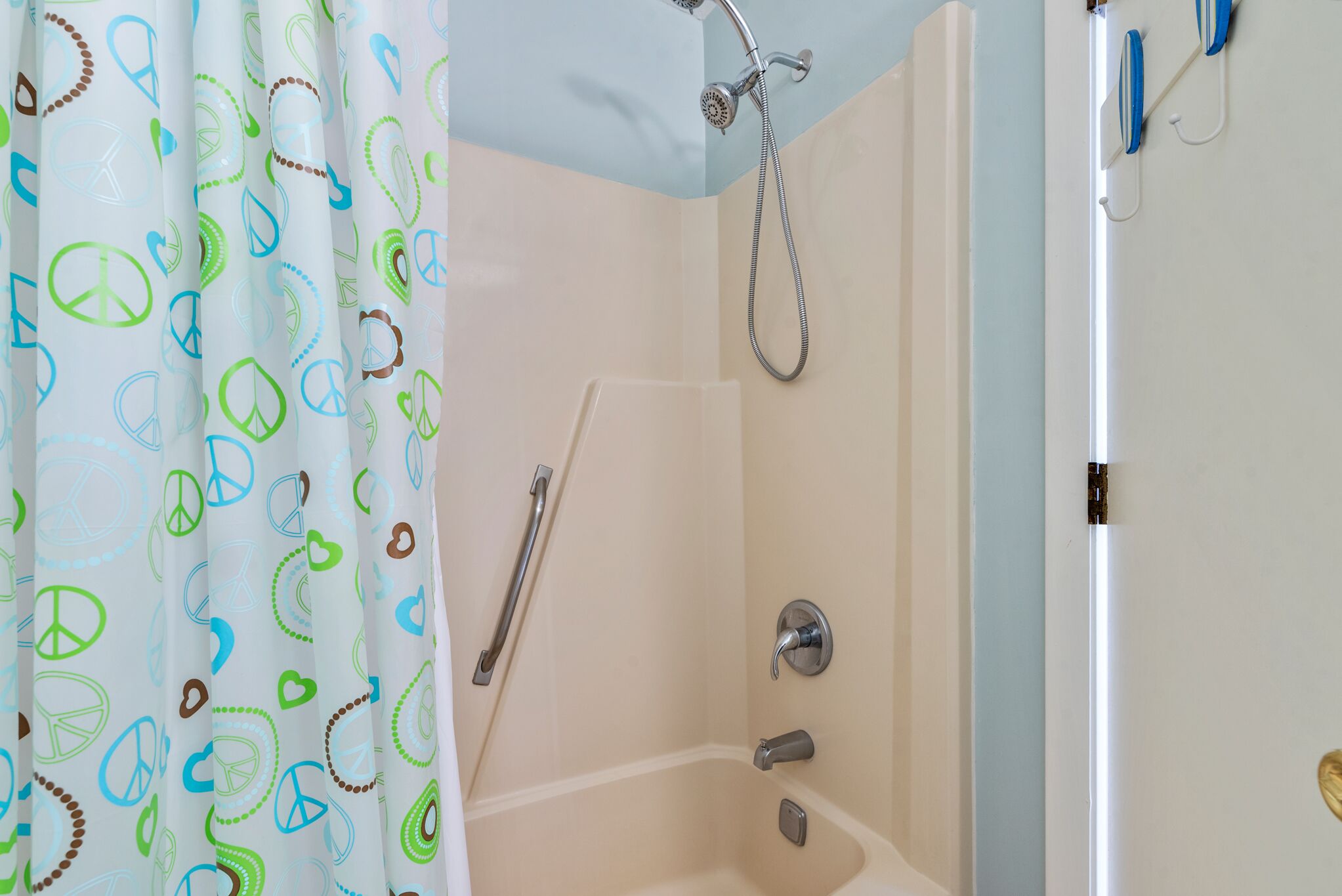 Un baño con ducha, barra de apoyo y bañera.