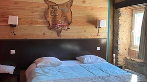 A bedroom with a wooden headboard, a bed with white bedding, a bedside table, and a wall-mounted decorative piece. - Gite in Cévennes (Saint-Christol-lès-Alès)