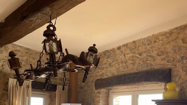 A rustic kitchen with a wooden counter, stone walls, a hanging light fixture, a window with a view, and a microwave. - Gite in Cévennes (Saint-Christol-lès-Alès)