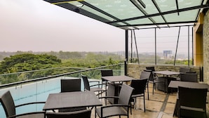 A terrace with outdoor seating and a view of a swimming pool. - Quality Inn Rockwell Grand, Bangalore (Bengaluru)