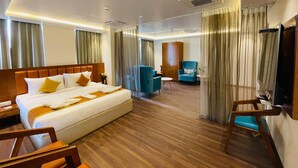 A hotel room with a large bed, a wooden headboard, a desk, a chair, a TV, and a wardrobe. - Quality Inn Rockwell Grand, Bangalore (Bengaluru)