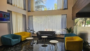 A lobby with a black marble floor, a grey sofa, and three round tables. - Quality Inn Rockwell Grand, Bangalore (Bengaluru)