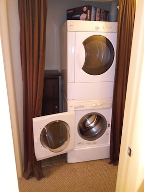 Un cuarto de lavandería con dos lavadoras apiladas y una secadora.