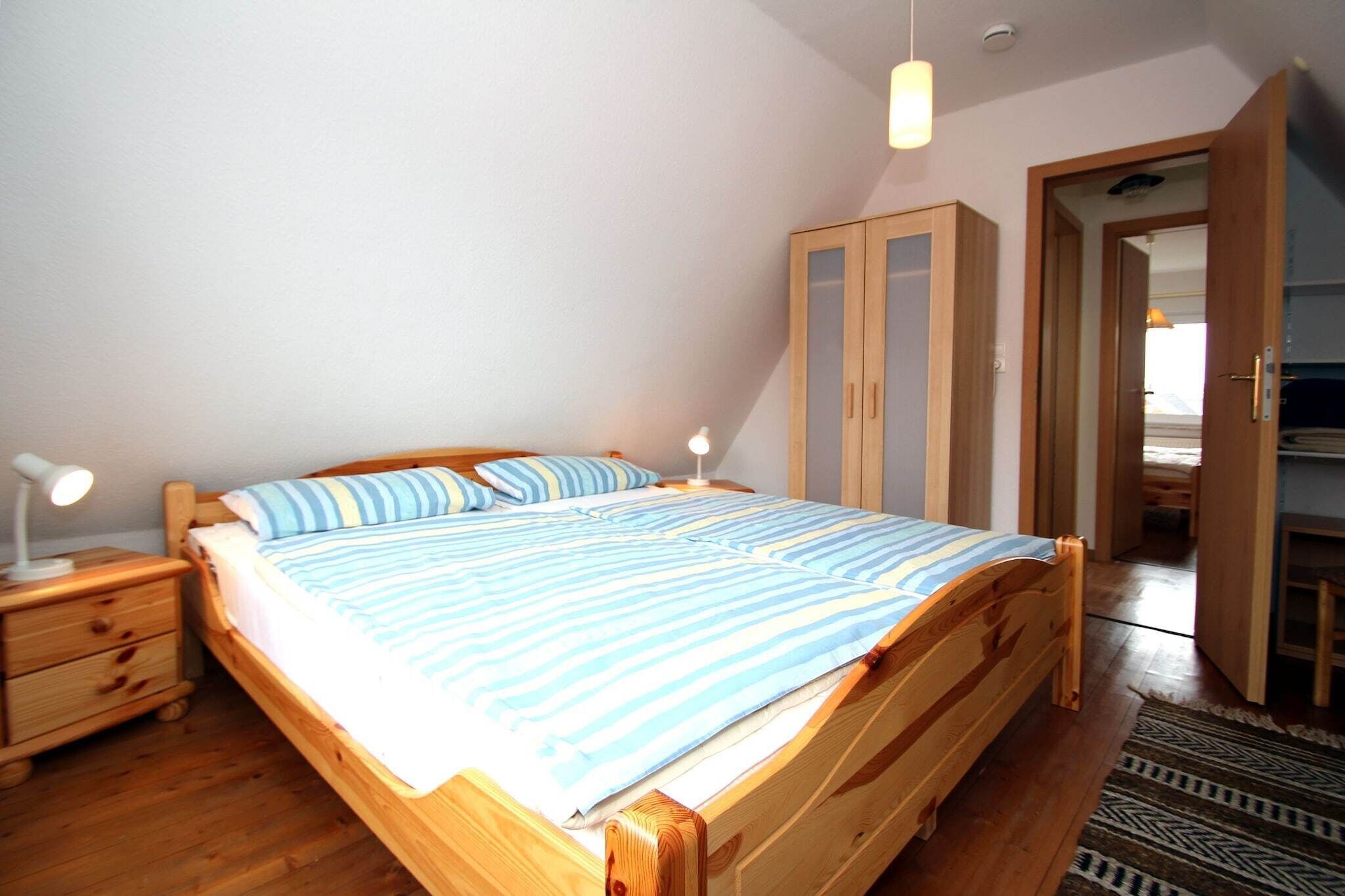 Un dormitorio con una cama de madera, una mesita de noche con lámpara y un armario.