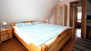 A bedroom with a wooden bed, a nightstand with a lamp, and a wardrobe. - Greetjehaus mit Garten, Nähe Strand, Dornumersiel (Dornumersiel)