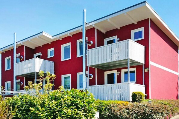 A red building with white balconies and multiple windows.