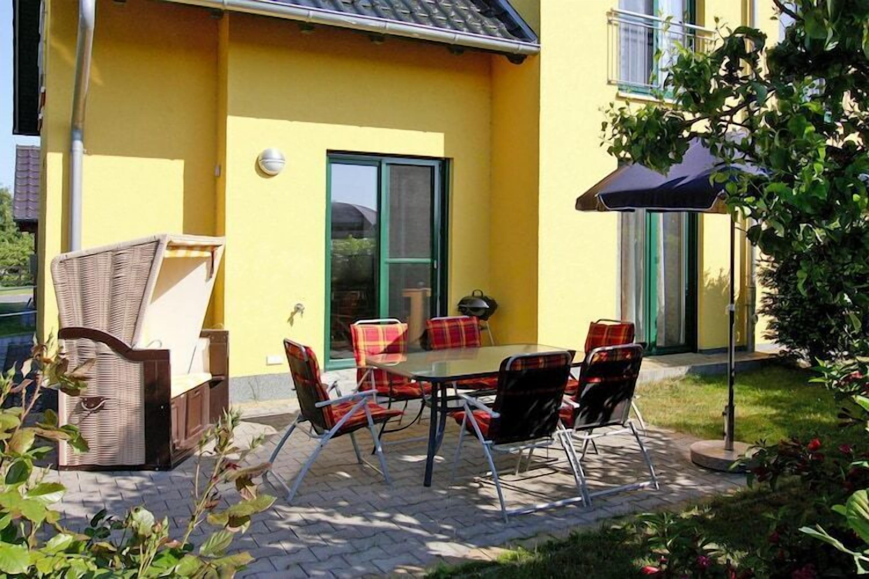 An outdoor patio with a table and chairs, a wicker sofa, and a blue umbrella.