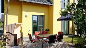 An outdoor patio with a table and chairs, a wicker sofa, and a blue umbrella. - Doppelhaushaelfte am Hafen von Neuendorf (Neuendorf)