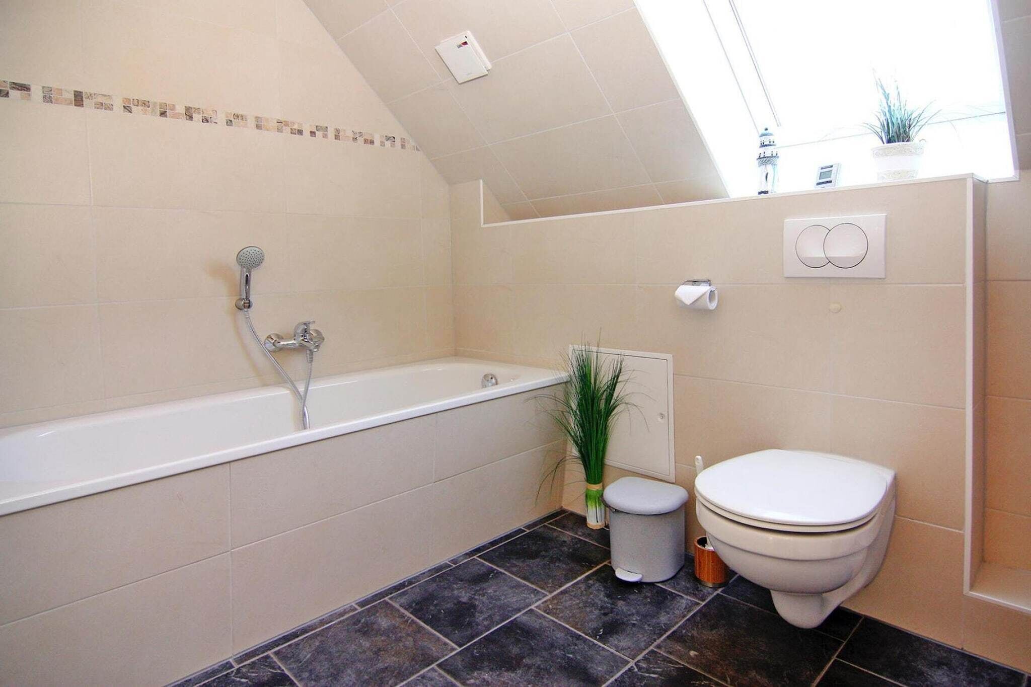 A bathroom with a bathtub, toilet, and a small potted plant.