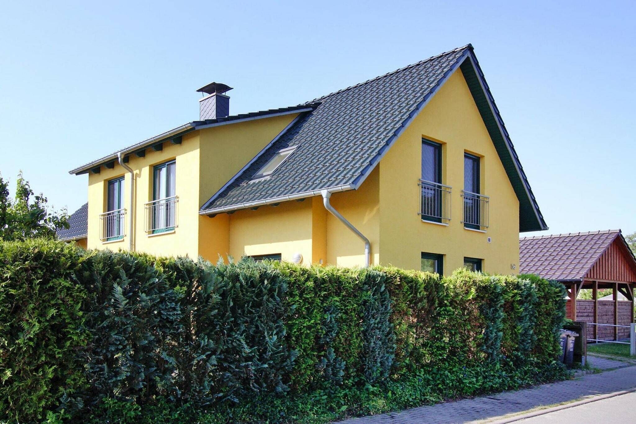 Una casa amarilla con techo inclinado, una chimenea y un balcón.