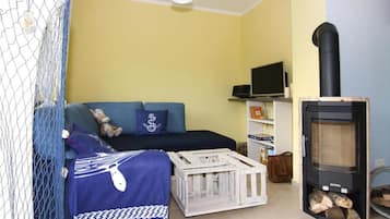 Ein gemütliches Wohnzimmer mit einer Couch, einem Fernseher, einem Kamin und einem kleinen Tisch.