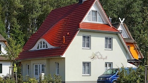 A two-story building with a red-tiled roof and a sign that reads "Machtigall". - Ferienhaus Nachtigall, Glowe (Glowe)