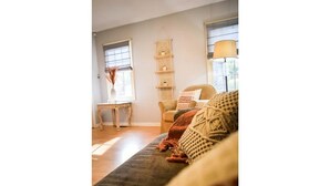 Ein gemütliches Wohnzimmer mit einer Couch, einem Sessel, einem kleinen Tisch und einer Lampe.