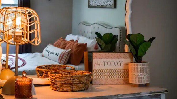 Ein ordentlich eingerichtetes Schlafzimmer mit einem Bett, dekorativen Körben, einem Schild und einer Lampe.