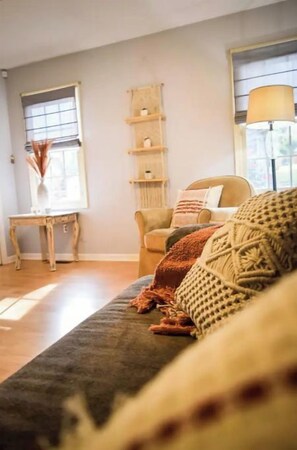A cozy living room with a sofa, a chair, a small table, and a lamp.