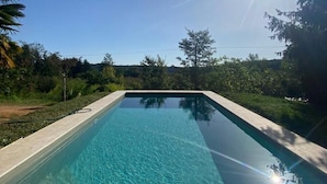 A rectangular swimming pool with clear water, surrounded by a concrete deck and bordered by trees and greenery. - Charming cottage  in the heart of nature with panoramic views  (Journiac)