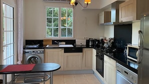 A modern kitchen with a dining area, a washing machine, a microwave, and a dishwasher. - Charming cottage  in the heart of nature with panoramic views  (Journiac)