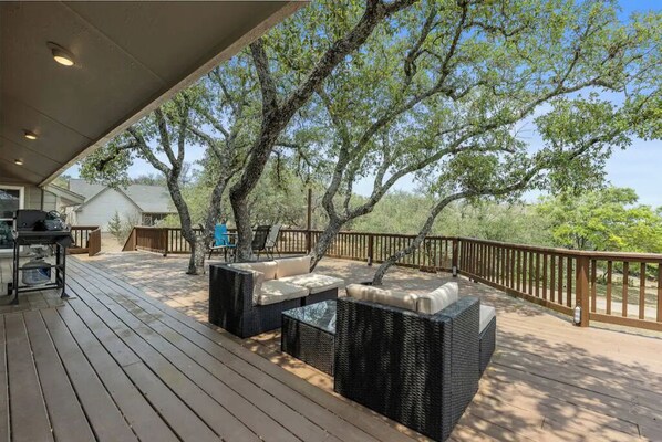 A covered outdoor deck with wicker furniture and a barbecue area.