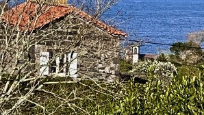 A stone building with a red-tiled roof, situated by the sea.