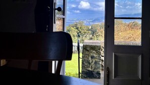 A room with a view of a cloudy sky and a distant landscape through an open door.