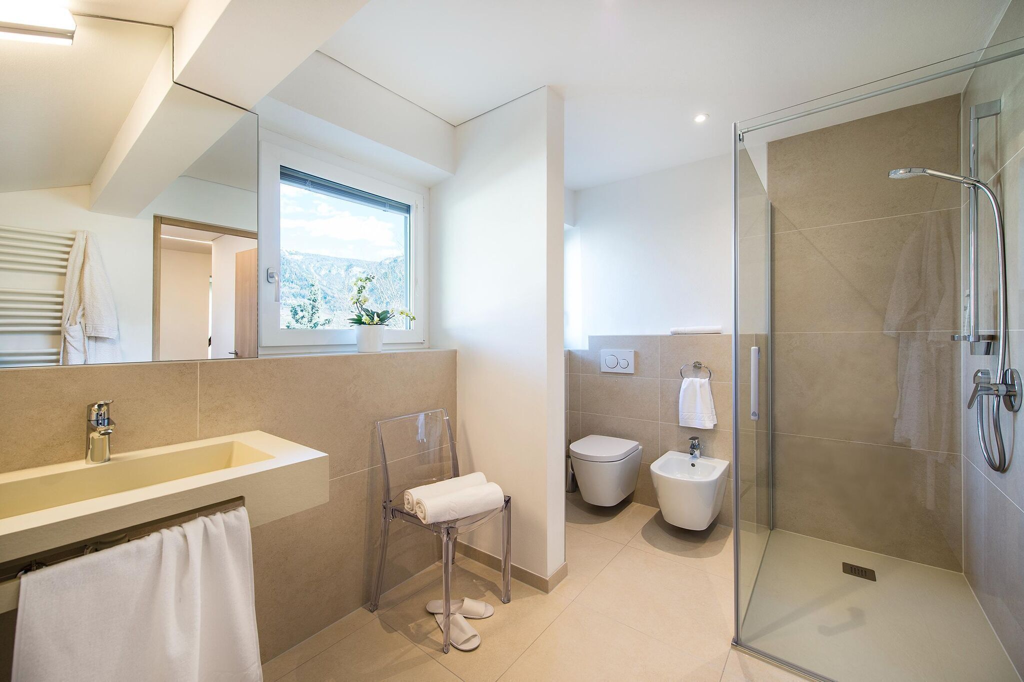 Ein modernes Badezimmer mit einem großen Waschbecken, einer Duschkabine aus Glas und einer Toilette.