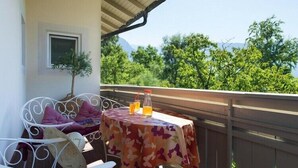 A balcony with a table, chairs, and a view of trees and mountains. - Apartment in Dorf Tirol near Tirol Castle (Dorf Tirol)