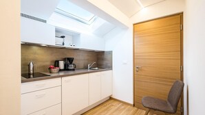 A modern kitchen with white cabinets, a wooden countertop, a coffee maker, and a skylight. - Apartment in Dorf Tirol near Tirol Castle (Dorf Tirol)