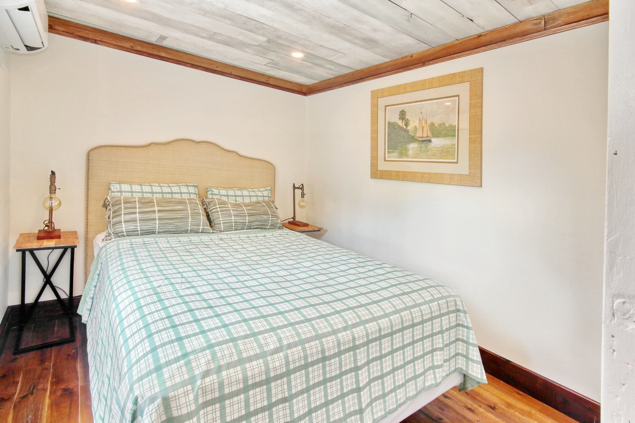 A bedroom with a bed, a nightstand, a lamp, and a framed picture on the wall.