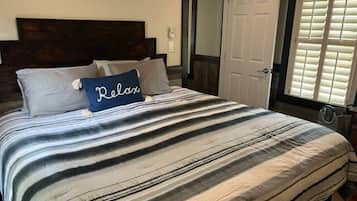 Una cama con ropa de cama a rayas y una almohada con la palabra 'Relax'.