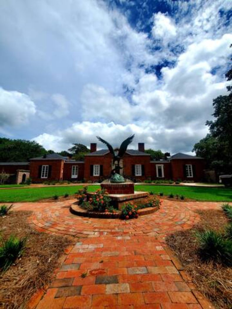 A brick building with a circular driveway leading to a central fountain.