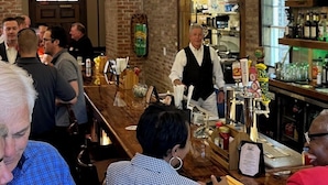A bar area with brick walls, wooden beams, and a counter with various bottles and glasses. - Wedgefield Country Club  (Georgetown)