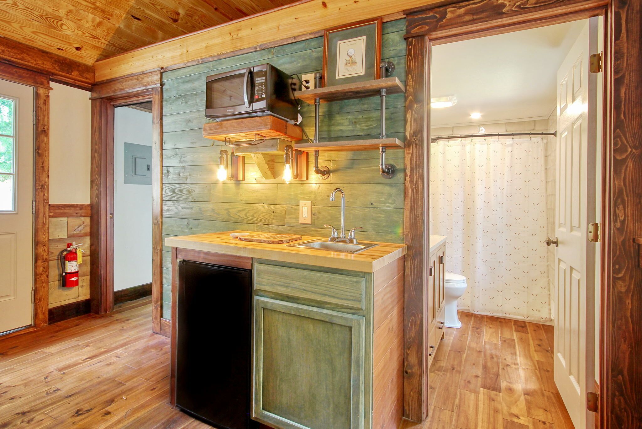 A compact kitchen with a built-in microwave, a sink, and wooden cabinetry.