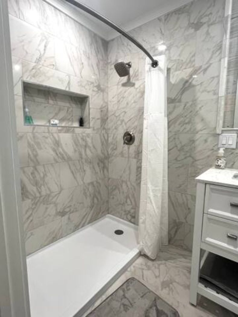 A bathroom with a shower, a sink, and a mirror.