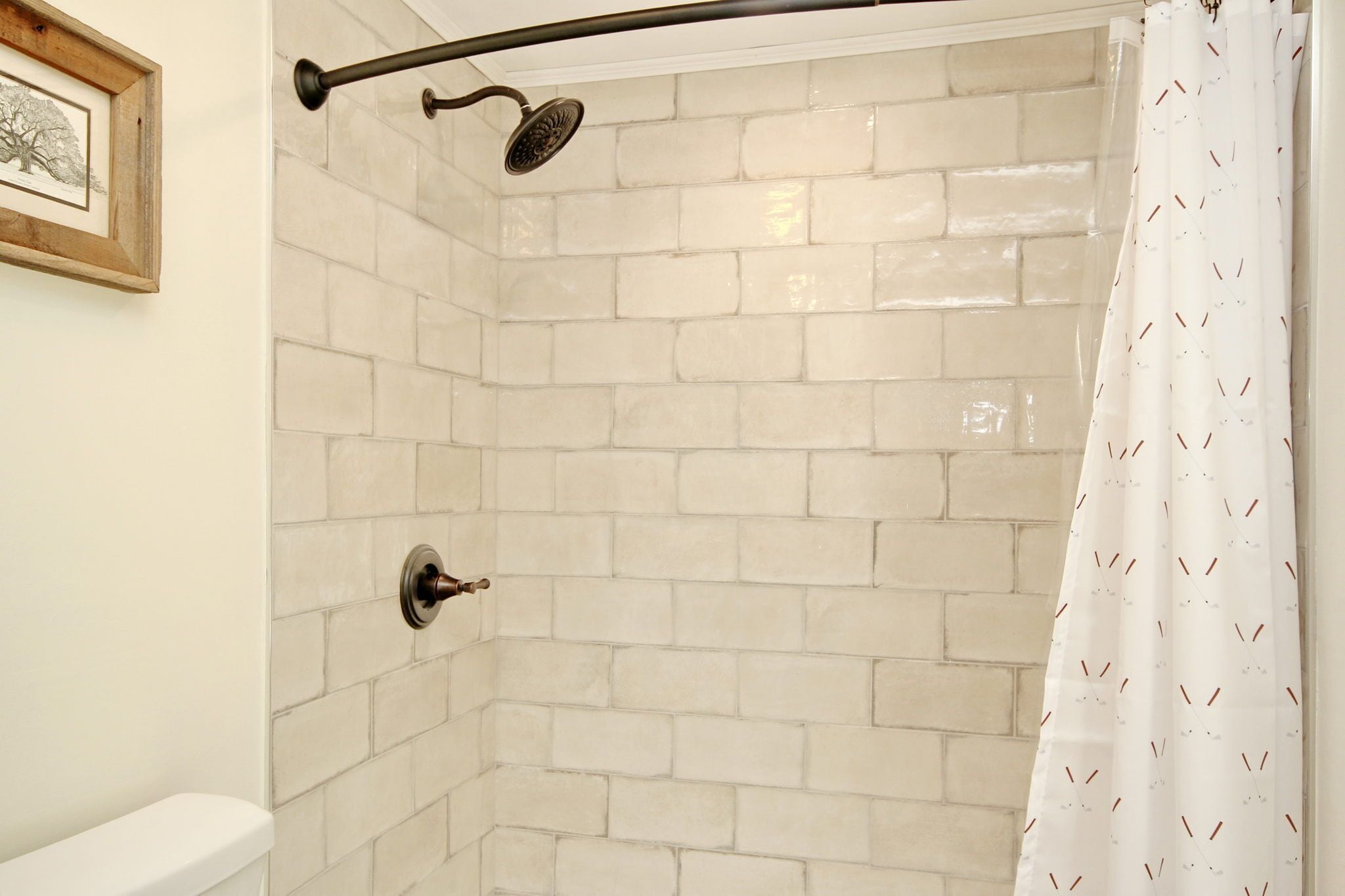 Une douche avec un mur en briques blanches, un pommeau de douche et un rideau.