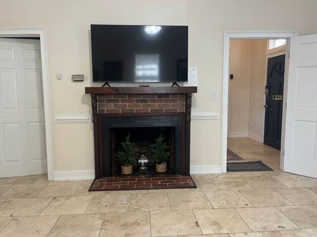 A living room with a fireplace, a television mounted above it, and a door leading to another room.