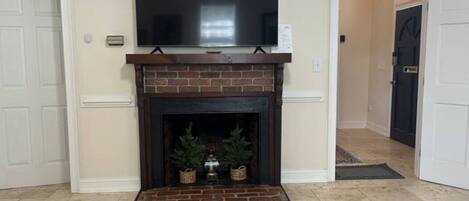 A living room with a fireplace, a television mounted above it, and a door leading to another room.