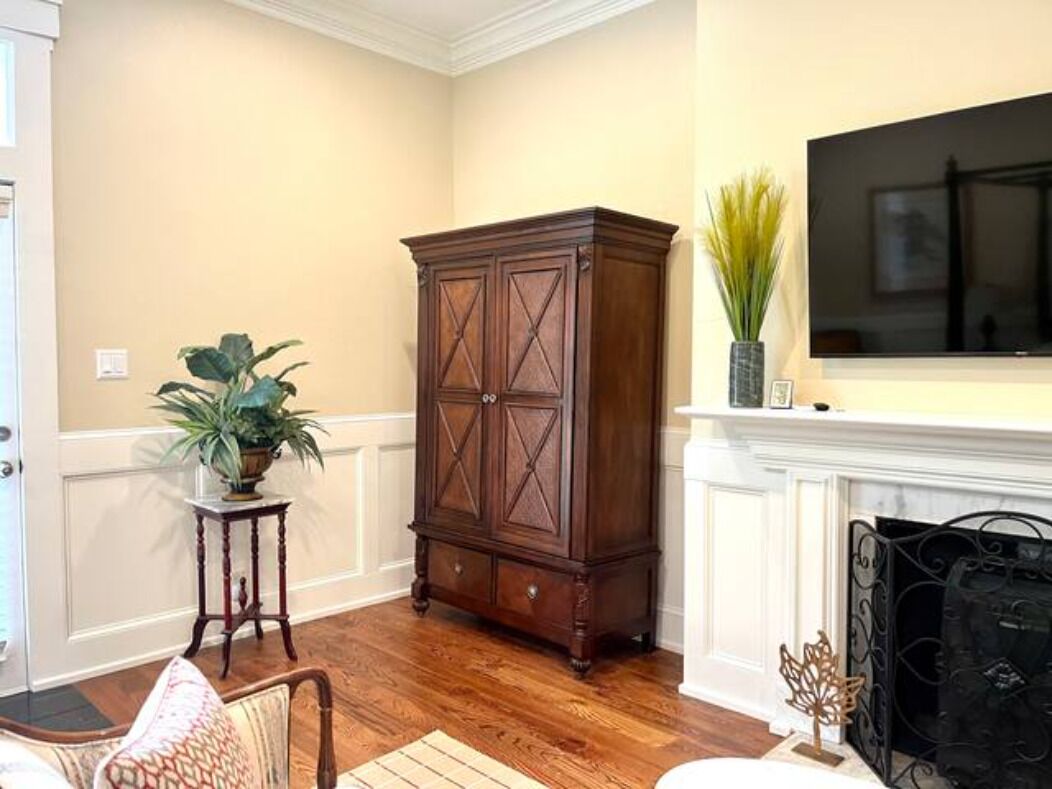 Una habitación con un armario de madera, una planta en maceta, una chimenea y un televisor colocado encima.