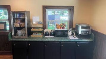 A breakfast bar with a refrigerator, microwave, and a window with a view of trees.