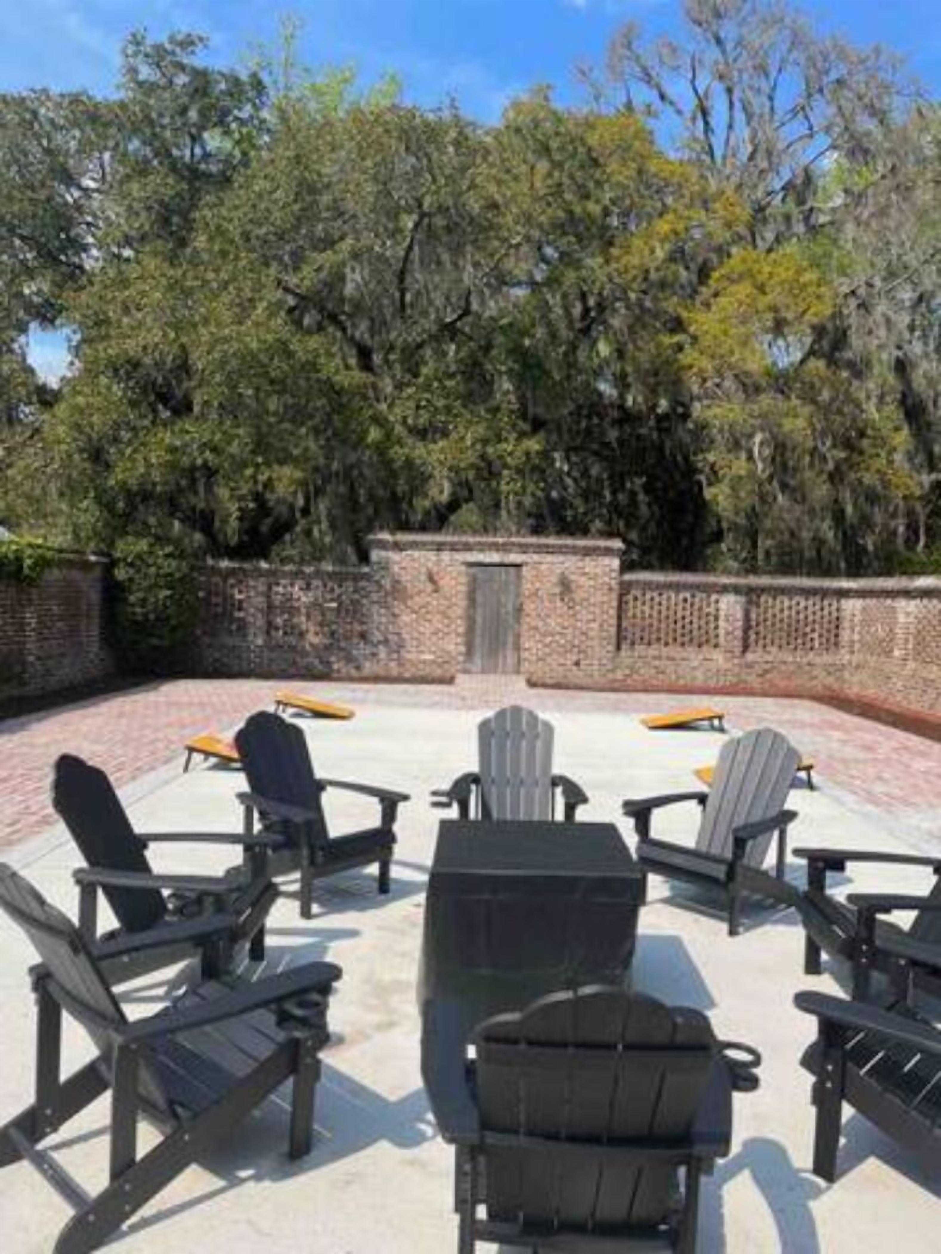 An outdoor seating area with Adirondack chairs and a brick wall.