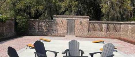 An outdoor seating area with Adirondack chairs and a brick wall.