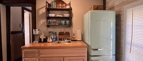 A compact kitchen with a wooden countertop, a built-in sink, and a vintage-style refrigerator.