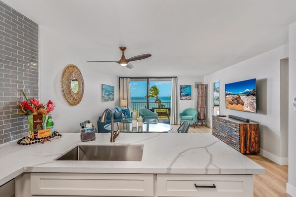 Una cucina moderna con una grande isola, un'area pranzo con vista e un soggiorno con balcone che si affaccia sull'oceano.