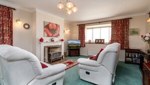 A living room with two reclining chairs, a fireplace, a television, and a bookshelf. - A detached, dog-friendly bungalow with a large garden near Abergele (Abergele)