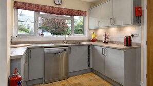 A modern kitchen with grey cabinets, a Bosch dishwasher, a red fire extinguisher, and a window with a view of the outside. - Cosy family cottage close to Beddgelert and Porthmadog (Porthmadog)