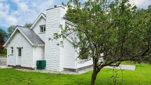A white stone cottage with a sloped roof, a chimney, and a green door. - Cosy family cottage close to Beddgelert and Porthmadog (Porthmadog)